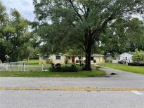 Charming single-story home with a well-manicured lawn, red door, and mature trees at 15034 Lake Magdalene Blvd, Tampa, FL 33618