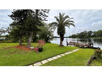 Beautiful waterfront view with a dock, lush greenery, and a paver walkway to the water at 19036 Blake Rd, Odessa, FL 33556