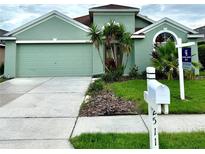Charming single-story home with a well-manicured lawn, palm trees, and a two-car garage, all painted in a welcoming green hue at 2511 Indian Key Dr, Holiday, FL 34691