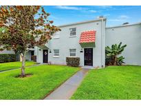 Charming townhouse featuring a well-manicured lawn and unique red awning detail over the front door at 2834 Somerset Park Dr, Tampa, FL 33613
