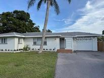 Charming single-story home with a well-maintained lawn, a palm tree and a driveway at 3118 Adrian Ave, Largo, FL 33774