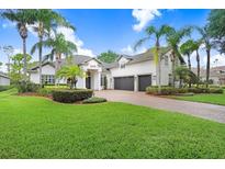 Beautiful home with lush landscaping, palm trees, and a circular brick driveway at 3519 Old Course Ln, Valrico, FL 33596