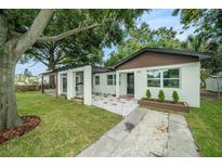 Charming single-story home with white exterior, stylish landscaping and a welcoming pergola-covered entry at 3812 W Rogers Ave, Tampa, FL 33611
