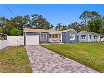 Charming blue home featuring an attached garage, a welcoming front porch, and a beautifully paved driveway at 4012 N Munro St, Tampa, FL 33603