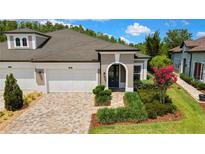 Beautiful single-story home featuring a brick driveway, three-car garage, and lush landscaping at 4155 Barletta Ct, Wesley Chapel, FL 33543