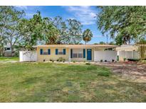 Charming yellow home with blue shutters, a well-maintained lawn and welcoming curb appeal on a sunny day at 4714 W Vasconia St, Tampa, FL 33629