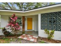 Welcoming home entrance featuring a vibrant yellow door and mid-century modern design accents at 1311 W Perdiz St, Tampa, FL 33612