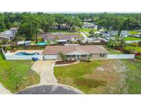 Aerial view of a ranch-style home featuring a fenced backyard with an in-ground pool and a driveway leading to the garage at 1410 Moss Laden Ct, Brandon, FL 33511