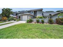 Charming townhome with lush front lawn, flowering shrubs, and an attached single car garage at 184 Hunter Ct, Palm Harbor, FL 34684