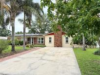 Ranch-style home with well-manicured lawn, red brick details, a long concrete driveway, and mature palm trees at 2523 Krueger Lane, Tampa, FL 33618