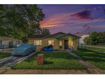 Charming bungalow with a well-maintained lawn and covered car at sunset at 3201 E Mcberry St, Tampa, FL 33610