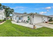 Charming home exterior featuring a cozy patio area, lush green lawn, and attached garage at 3271 Mcmath Dr, Palm Harbor, FL 34684