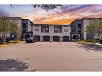 Condominium building with garages and black car parked in front during daytime with nicely landscaped yard at 8517 Island Breeze Ln # 207, Temple Terrace, FL 33637