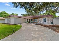 Charming single-story home with a well-manicured lawn, stone accents and a curved driveway at 2824 Paddock Dr, Palm Harbor, FL 34684