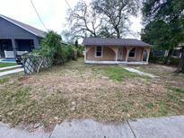 Charming single-story home featuring a cozy front porch and a yard with mature trees, offering great curb appeal at 8718 N Brooks St, Tampa, FL 33604