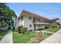 Inviting two-story condo with a balcony, manicured lawn and walkway under a blue sky at 9945 47Th N Ave # 210, St Petersburg, FL 33708