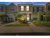 Charming townhouse featuring manicured landscaping, a decorative wreath and American flag at 1044 Kennewick Ct, Wesley Chapel, FL 33543