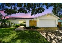 Charming single Gathering home with manicured lawn and a two car garage with a brick walkway at 1286 Stony Brook Ln, Dunedin, FL 34698