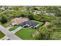 Beautiful aerial view of the house, showcasing its dark roof, green lawn, and proximity to lush greenery at 14009 Wenzel Ave, Port Charlotte, FL 33981