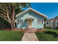 Charming bungalow featuring a manicured lawn, mature tree, and inviting yellow door at 1525 38Th N Ave, St Petersburg, FL 33704