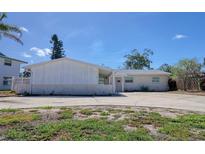 Charming single-story home with a brick facade, large driveway, and well-maintained landscaping under a clear blue sky at 1897 Dolphin S Blvd, St Petersburg, FL 33707