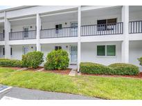 Inviting condo exterior with white facade, black railings, and lush landscaping at 2060 Marilyn St # 114, Clearwater, FL 33765