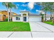 Charming single-story home with a well-manicured lawn, arched entryway, and two-car garage at 25729 Aldus Dr, Land O Lakes, FL 34639