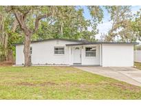 Charming renovated single-story home featuring a modern white exterior and well-maintained front lawn at 4220 E Regnas Ave, Tampa, FL 33617
