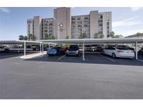View of parking lot with covered parking spaces with The International building in the background at 7600 Sun Island S Dr # 603, South Pasadena, FL 33707