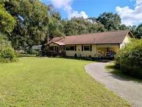 Ranch style home featuring mature trees and landscaping, long driveway and neutral color palette at 7608 Chenkin, Zephyrhills, FL 33540