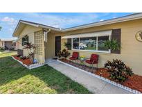 Charming home featuring well-manicured landscaping and a cozy seating area on the front porch at 9892 111Th St, Seminole, FL 33772