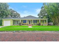 Charming single-story home with green exterior and welcoming front porch, complemented by a well-manicured lawn at 204 W Calhoun St, Plant City, FL 33563