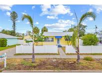 Charming yellow home with blue accents, palm trees, and a white picket fence at 260 42Nd Ave, St Pete Beach, FL 33706