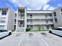 Condominium building with white facade, outdoor stairwell, and parking lot in front at 2625 State Road 590 # 1012, Clearwater, FL 33759