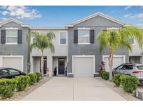 Charming townhome with a well-maintained front yard, lovely palm trees, and a one car garage at 2771 Suncoast Blend Dr, Odessa, FL 33556