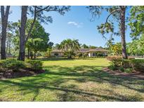 Beautifully landscaped front yard with lush green grass and mature trees framing the charming home at 3452 Forelock Rd, Tarpon Springs, FL 34688