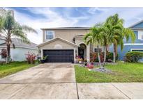 Charming two-story home with a well-maintained lawn and landscaping featuring palm trees and flowering plants at 533 Vista Ridge Dr, Ruskin, FL 33570