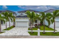 Beautiful two-story home with lush landscaping, a patterned driveway, and a white three-car garage at 6528 Simone Shores Cir, Apollo Beach, FL 33572