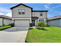Charming two-story home with a well-manicured lawn, lush landscaping and attached two-car garage at 6658 Devlin Ln, Wesley Chapel, FL 33545