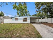 Charming single-story home featuring a covered carport and a well-maintained front yard with a white picket fence at 8556 91St Ter, Seminole, FL 33777