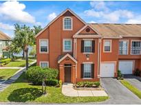 Charming two-story townhome featuring an attached garage and landscaped front yard with a beautiful blue sky backdrop at 9842 Lake Chase Island Way, Tampa, FL 33626