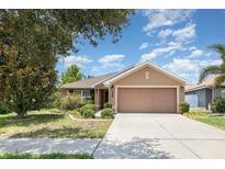 Charming single-story home featuring a two-car garage and well-maintained landscaping at 10847 Kirkwall Port Dr, Wimauma, FL 33598