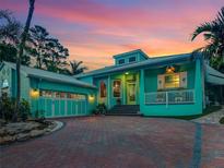 Beautiful two-story home with a vibrant exterior paint, brick driveway, and lush tropical landscaping at 1217 N Florida Ave, Tarpon Springs, FL 34689