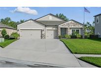 Well-maintained home with a three-car garage, stone accents, and a lush green lawn at 12593 Retreat Pl, Spring Hill, FL 34610