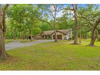 Charming single-Gathering home features a spacious front yard with mature trees and a two car garage at 19555 Phillips Rd, Brooksville, FL 34604