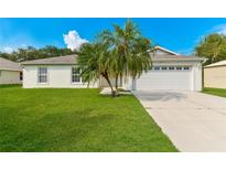 Charming one-story home featuring a manicured lawn and a palm tree accenting the front yard at 2718 Chipley Ave, North Port, FL 34286
