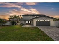 Stunning two-story home with a well-manicured lawn and a modern gray driveway leading to the two-car garage at 319 Midway Is, Clearwater Beach, FL 33767
