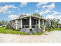 Charming home featuring a screened-in front porch, manicured landscaping, and a freshly painted exterior at 36725 Arcadia Ave, Myakka City, FL 34251