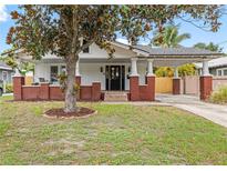 Charming two-story home with white siding, red brick accents, front porch, and covered carport at 400 E Jean St, Tampa, FL 33604