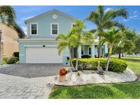 Beautifully landscaped two-story home with a two-car garage and vibrant turquoise exterior paint at 449 Bahama Grande Blvd, Apollo Beach, FL 33572